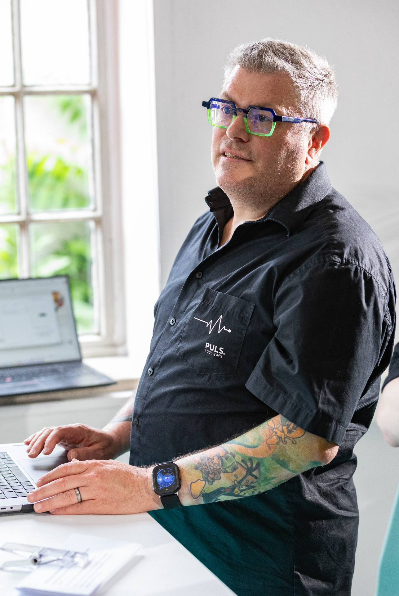 Oliver Puls im Gespräch an einem Arbeitsplatz mit Laptop